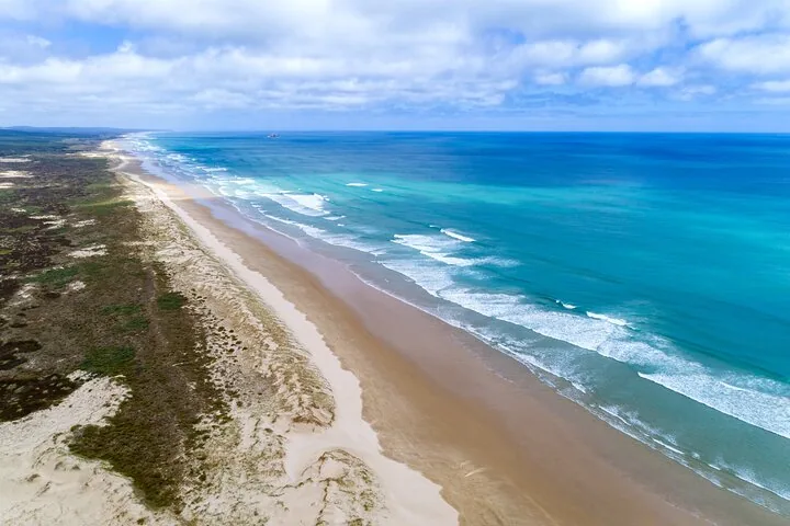 Luftaufnahme der langen Küstenlinie und der brechenden Wellen des Ninety Mile Beach.