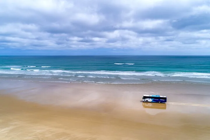 Luftaufnahme eines Reisebusses, der am weiten Ninety Mile Beach entlangfährt.