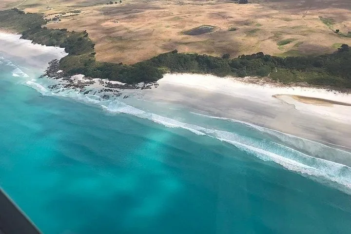 Veduta aerea di una spiaggia di sabbia bianca che incontra il mare blu cristallino.